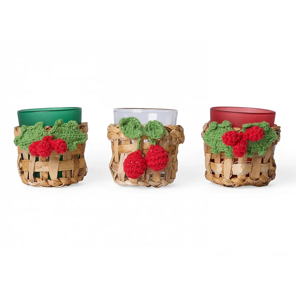 handcrafted banana bark woven tea light holders with green and red crochet holly berry accents holding colored glass candle cups on a festive table display