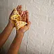 handcrafted banana bark fiber bell fairy lights emitting a warm amber glow against a textured white brick wall pattern
