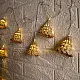 handcrafted banana bark fiber bell fairy lights emitting a warm amber glow against a textured white brick wall pattern