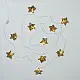 handcrafted banana bark fiber bell fairy lights emitting a warm amber glow against a textured white brick wall pattern