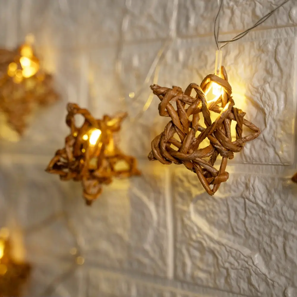handcrafted banana fiber rope star fairy lights emitting a warm amber glow against a textured white brick wall pattern