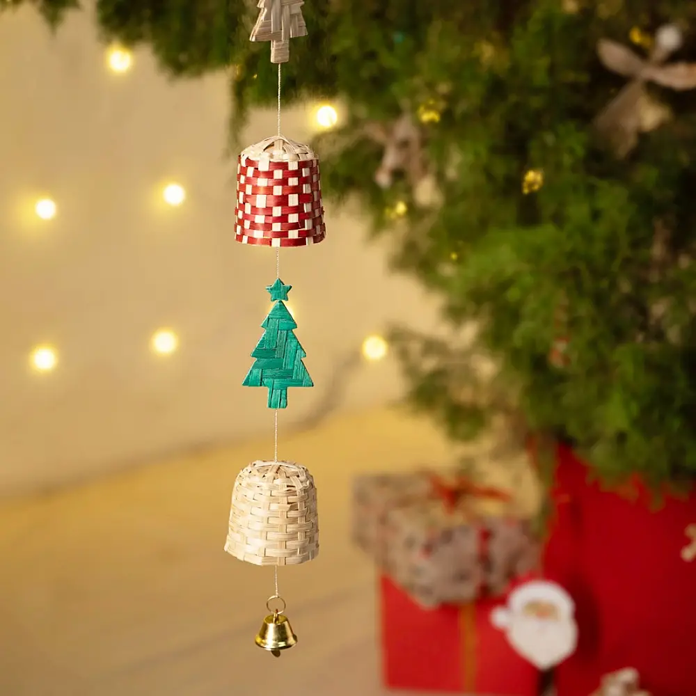 handcrafted vertical christmas string ornament featuring alternating red, green, and checkered bamboo trees and bells against a wooden wall panel