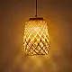 handcrafted woven bamboo twirl pendant light emitting a warm golden glow on a brown background wall