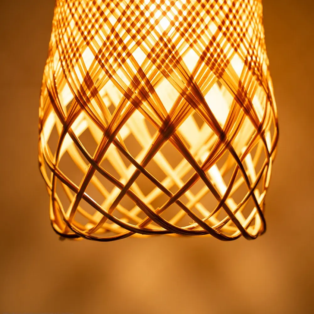 handcrafted woven bamboo twirl pendant light emitting a warm golden glow on a brown background wall