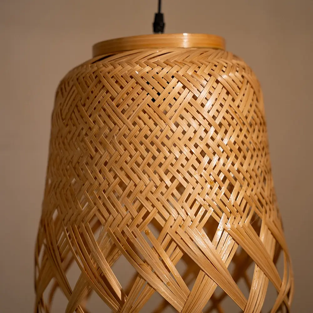 handcrafted woven bamboo twirl pendant light emitting a warm golden glow on a brown background wall