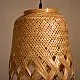 handcrafted woven bamboo twirl pendant light emitting a warm golden glow on a brown background wall