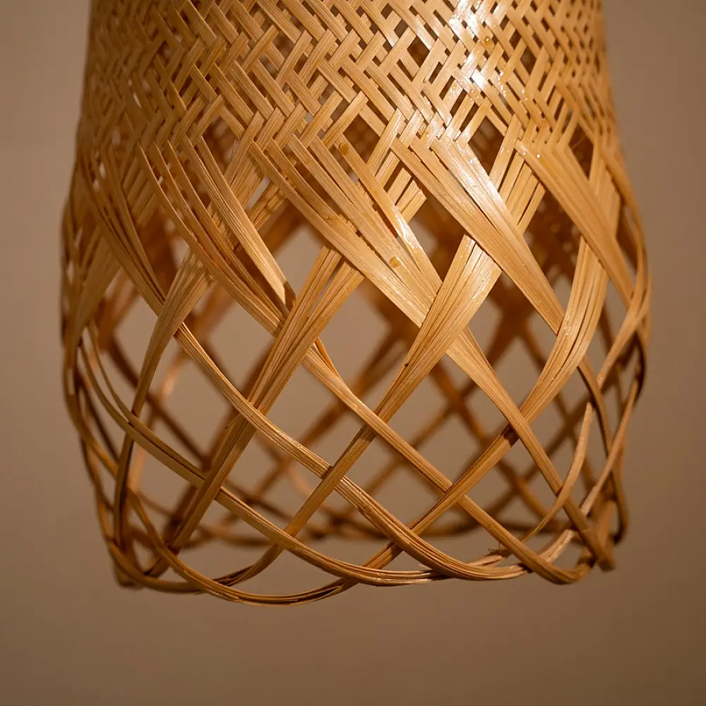 handcrafted woven bamboo twirl pendant light emitting a warm golden glow on a brown background wall