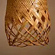 handcrafted woven bamboo twirl pendant light emitting a warm golden glow on a brown background wall