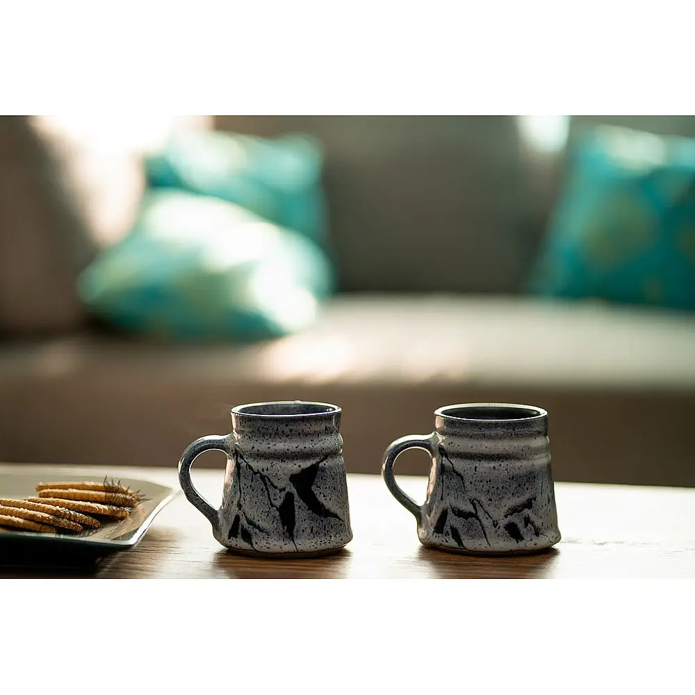 handmade studio ceramic coffee mugs set of two in light blue and white glaze with hand painted botanical leaf motifs