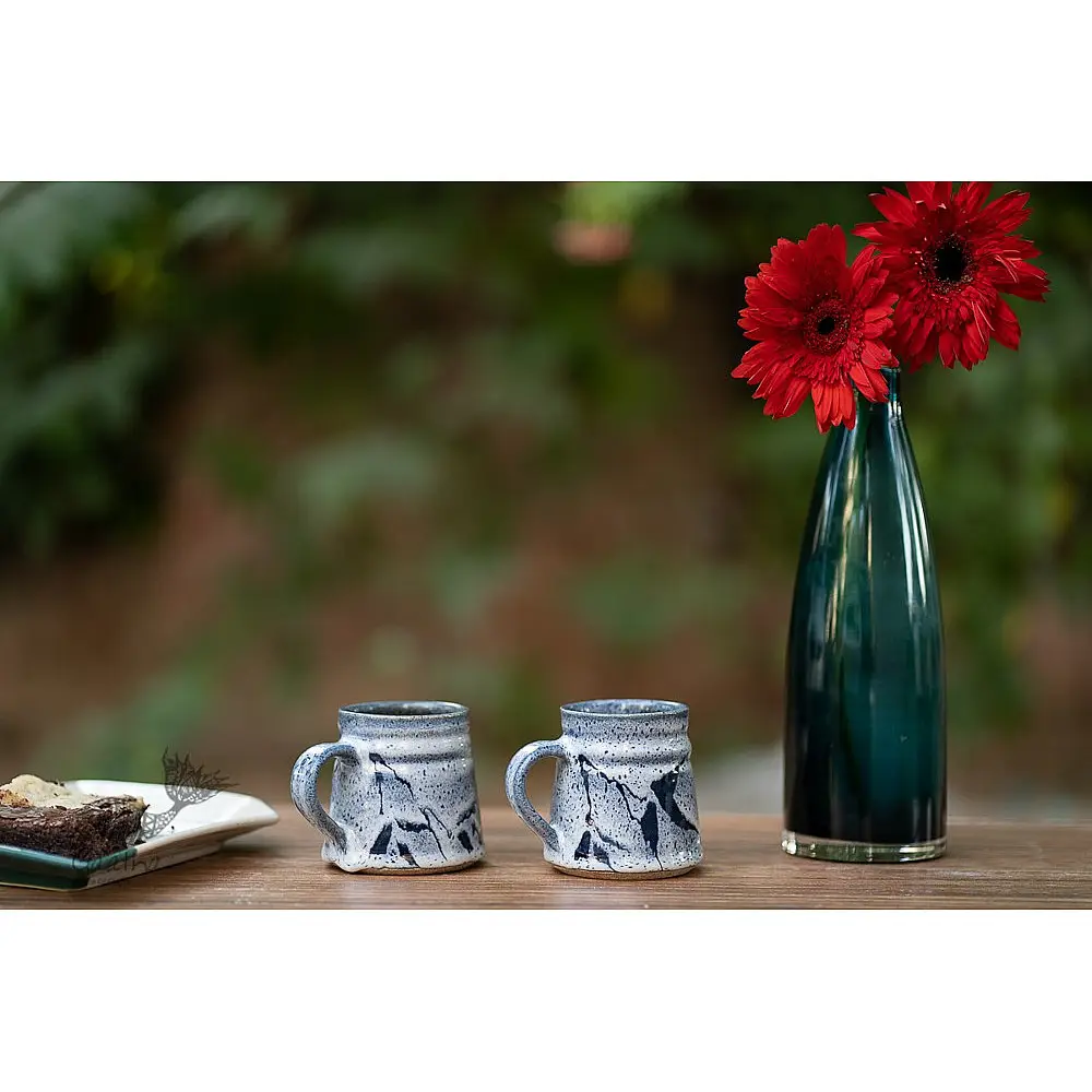 handmade studio ceramic coffee mugs set of two in light blue and white glaze with hand painted botanical leaf motifs