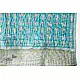 blue and teal block printed baby quilt with whimsical unicorns and rainbows pattern draped over a crib