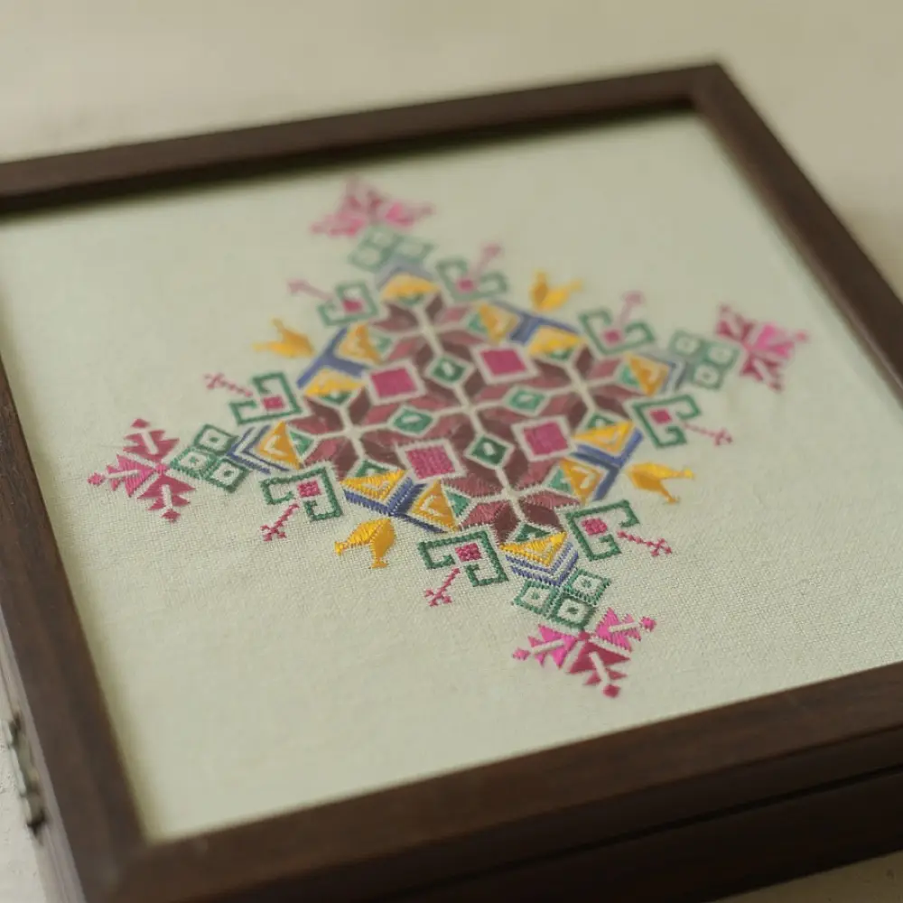 handcrafted square wooden box featuring an ivory fabric top panel with multi-color geometric Soof hand embroidery next to pink flowers