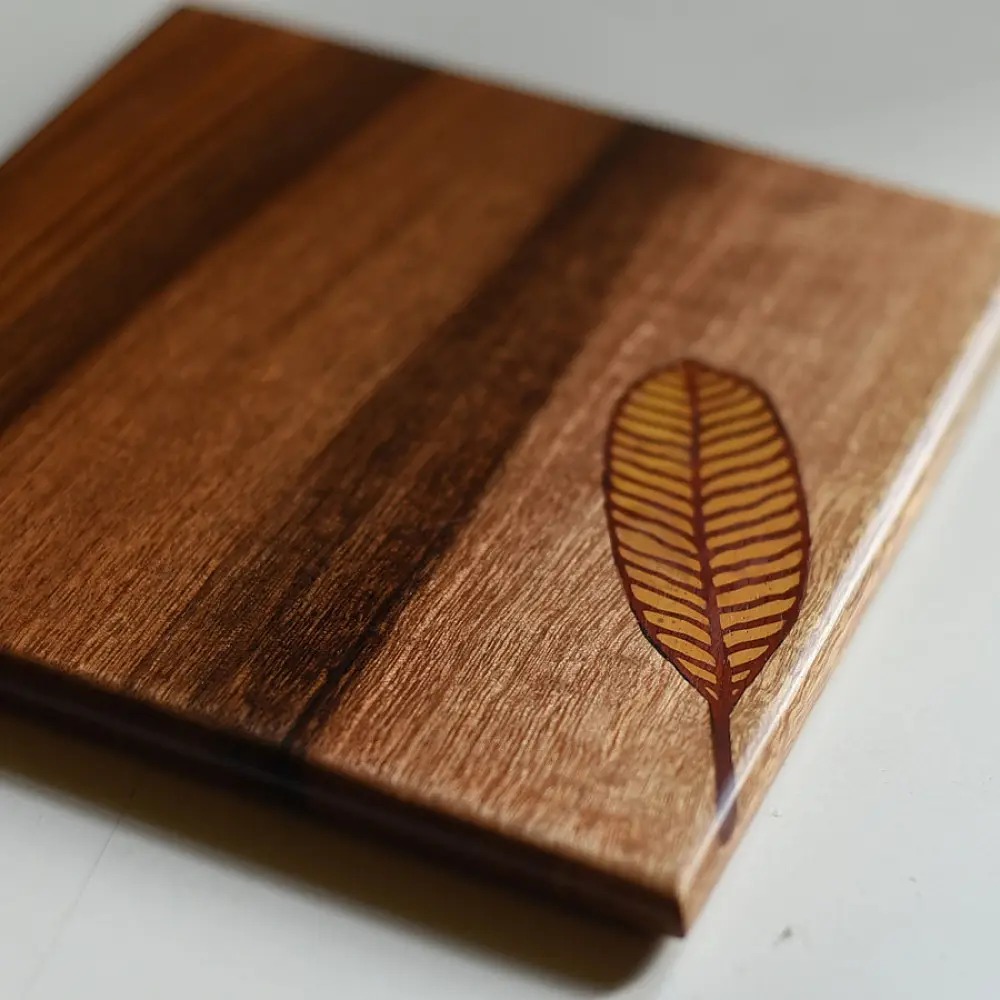 handmade wooden trivet with engraved leaf motif and two-tone finish