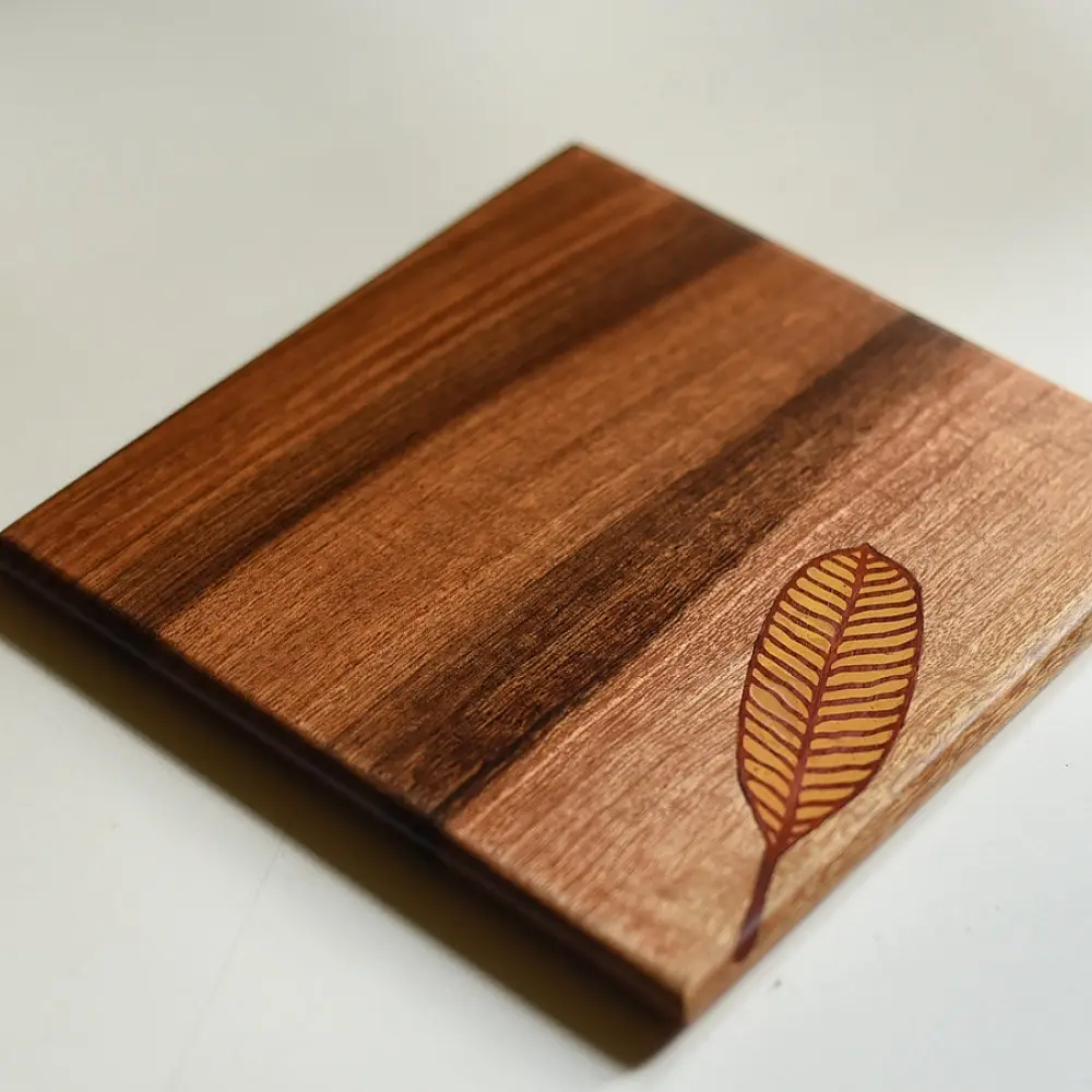 handmade wooden trivet with engraved leaf motif and two-tone finish