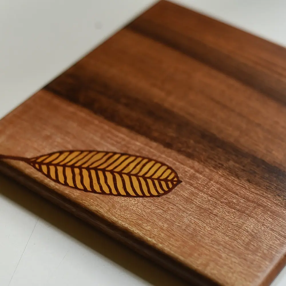 handmade wooden trivet with engraved leaf motif and two-tone finish