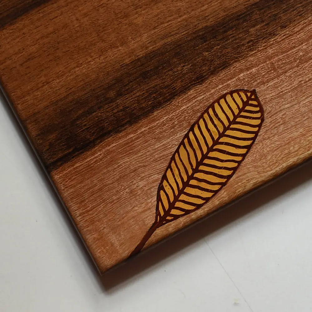 handmade wooden trivet with engraved leaf motif and two-tone finish