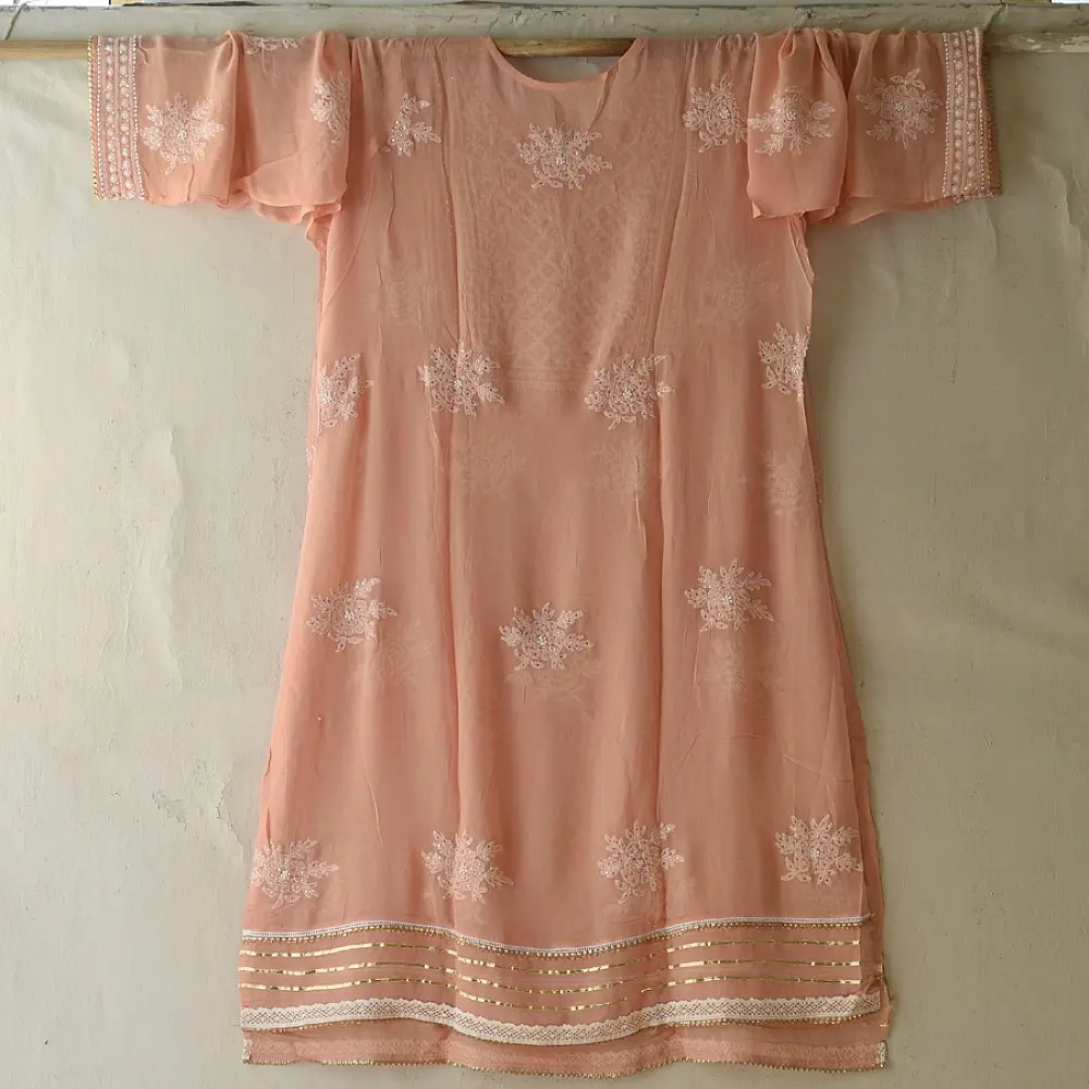 semi stitched viscose georgette kurti in delicate peach color featuring fine hand embroidered chikankari lattice yoke and all over floral motifs paired with a mukaish and lace detailed dupatta