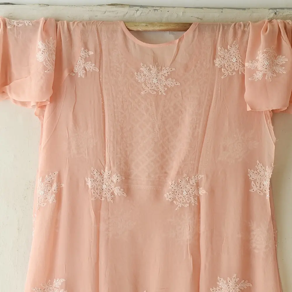 semi stitched viscose georgette kurti in delicate peach color featuring fine hand embroidered chikankari lattice yoke and all over floral motifs paired with a mukaish and lace detailed dupatta