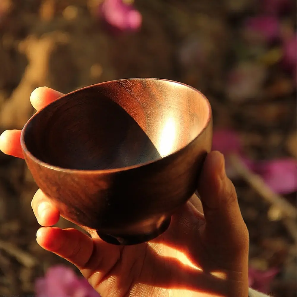 handmade walnut wooden bowl held in hand with deep rounded shape